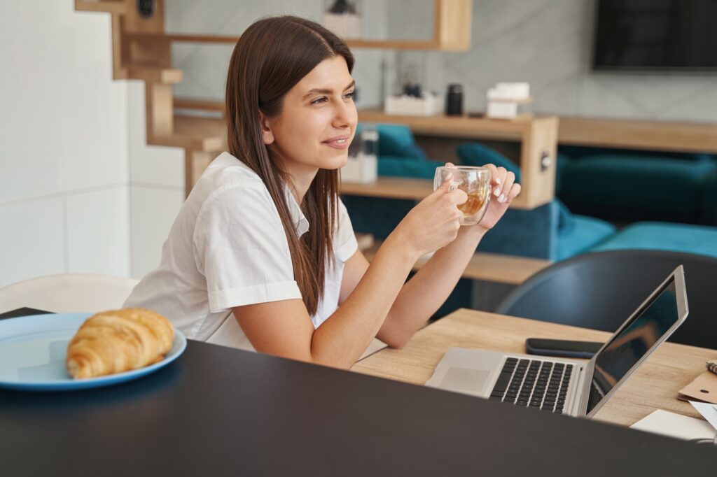 Caucasian female freelancer daydreaming at her laptop