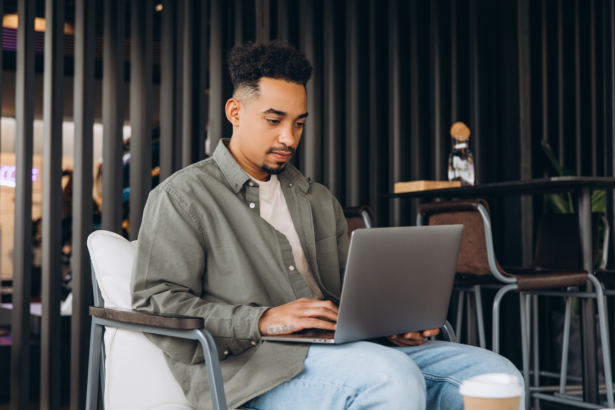 Focused freelancer working remotely on laptop in modern cafe
